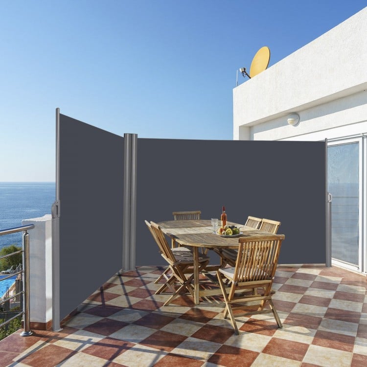 Patio retractable double folding side awning screen divider in use, providing privacy on a balcony with a wooden dining.