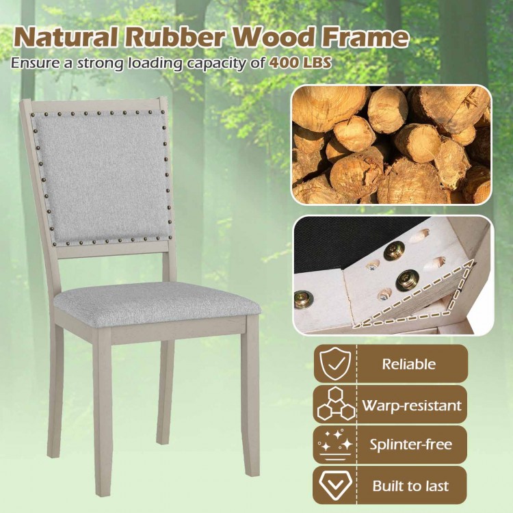 Farmhouse dining chair with grey fabric upholstery, rubber wood frame, and vintage nailheads for rustic elegance.
