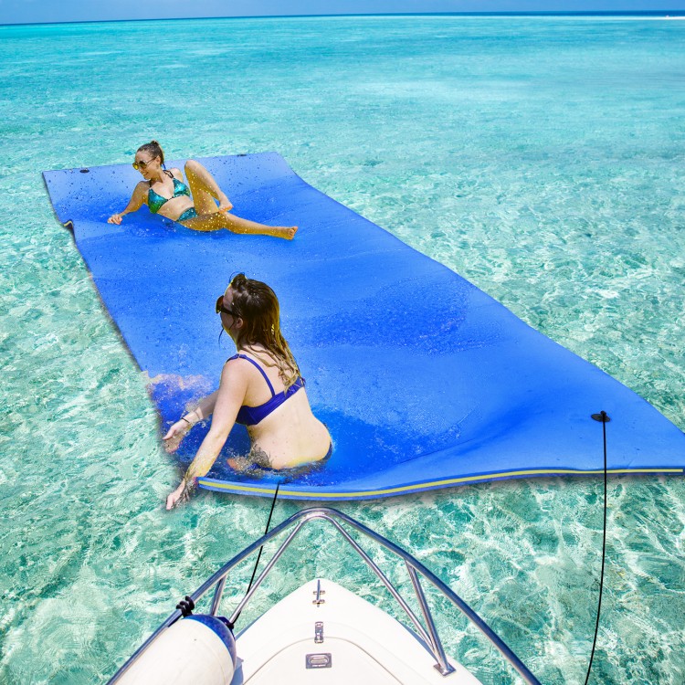 Two women relax on a 9' x 6' blue floating water pad made of eco-friendly XPE foam in clear water.