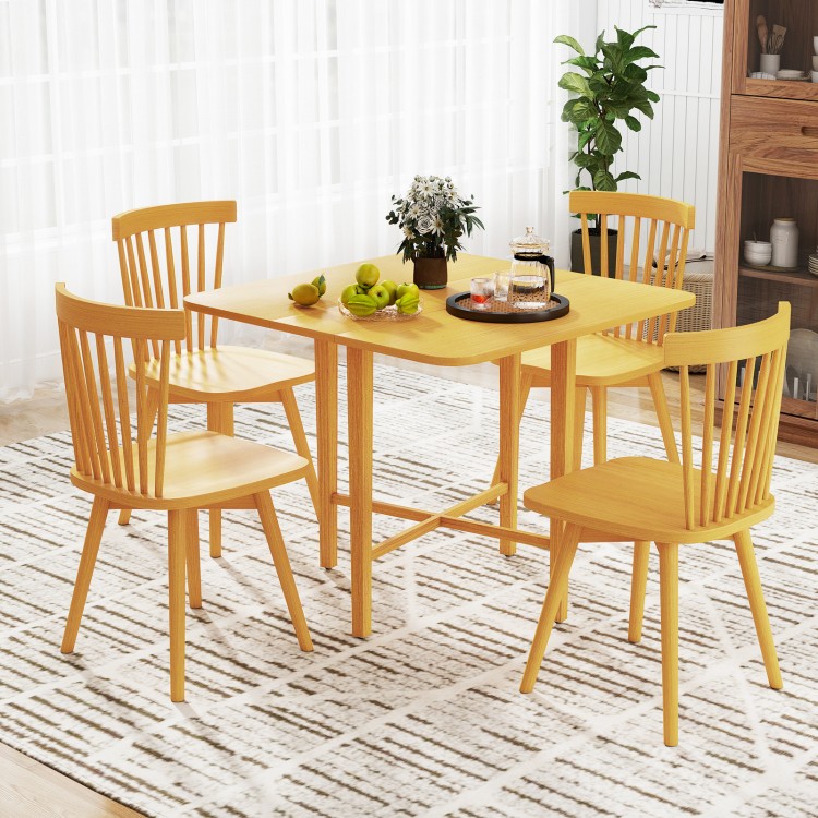 Foldable dining table with rubber wood legs, featuring drop leaf design, set for four in a cozy indoor setting.