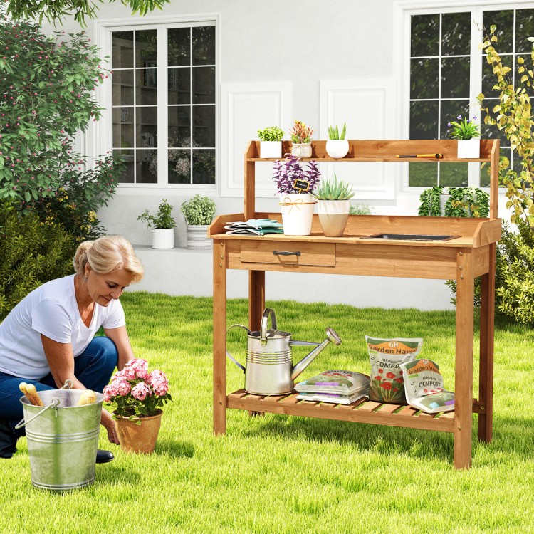 Outdoor wooden garden table work station with storage shelves, drawer, and removable sink for gardening tasks.