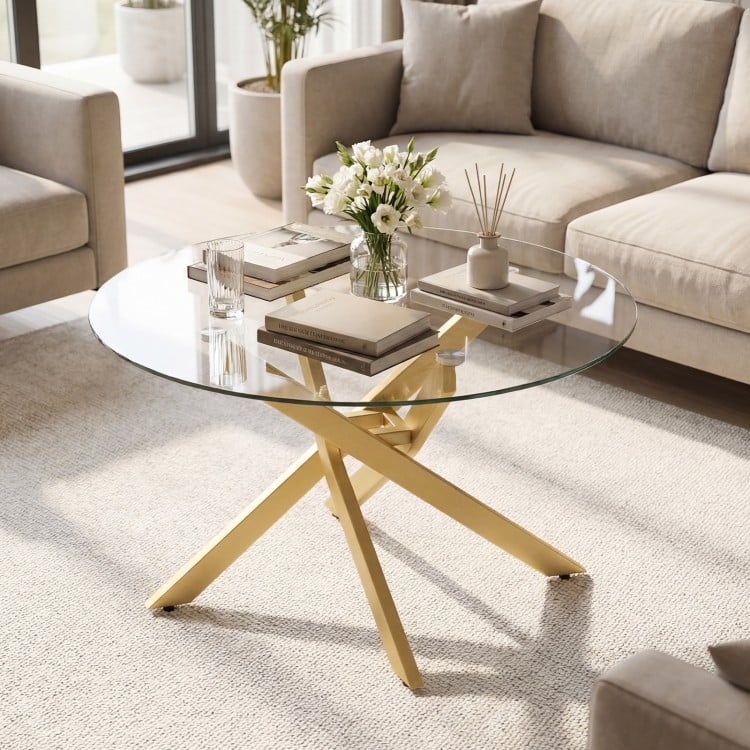 Round glass coffee table with a golden geometric metal frame, featuring a tempered glass top for modern living spaces.