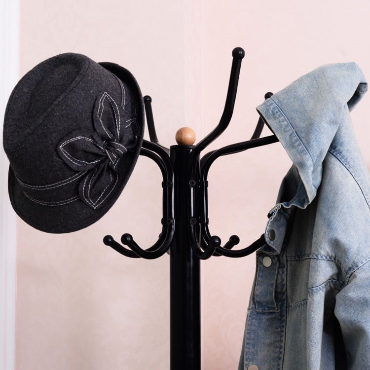 Vintage metal coat and hat tree stand with a stylish design, featuring a black finish and a hat and jacket hanging.