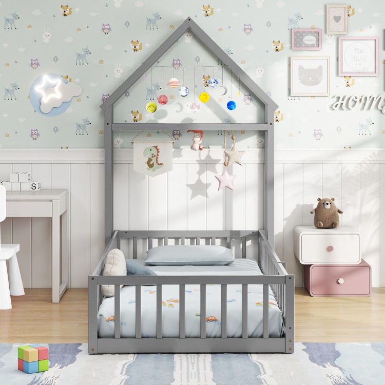 Twin size gray house floor bed with house-shaped headboard, low-to-ground design for easy access in a kid's room.