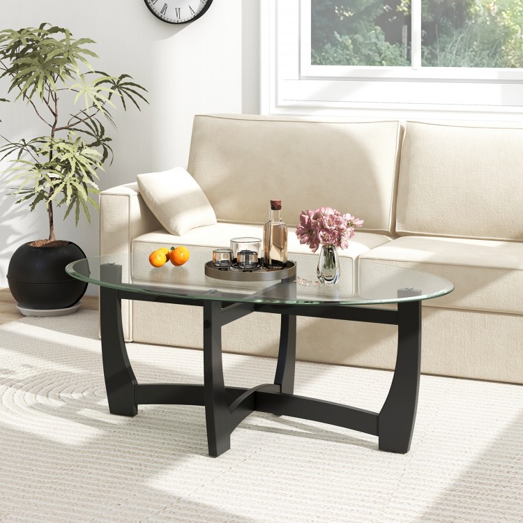 Oval coffee table with a smooth tempered glass surface and rubber wood legs, perfect for a cozy living room setting.