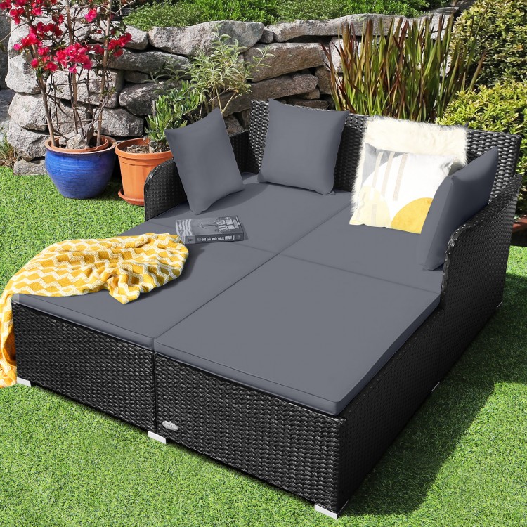 Spacious gray outdoor rattan daybed with upholstered cushions and armrests, perfect for relaxation in your garden.