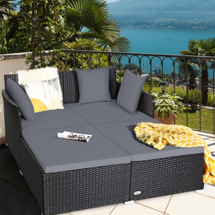 Spacious outdoor rattan daybed with gray upholstered cushions, perfect for relaxation on patios or balconies.