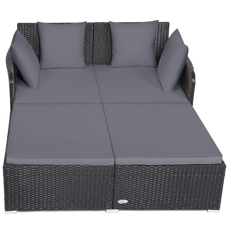 Spacious outdoor rattan daybed in gray with upholstered cushions, featuring armrests and a curved backrest for comfort.