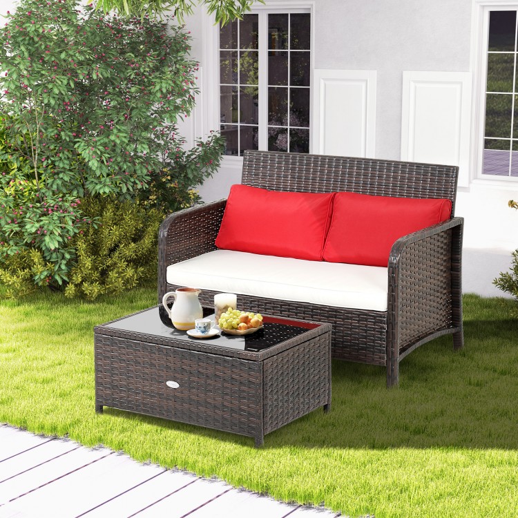 Wicker loveseat set with red cushions and coffee table, featuring ergonomic design for outdoor relaxation.