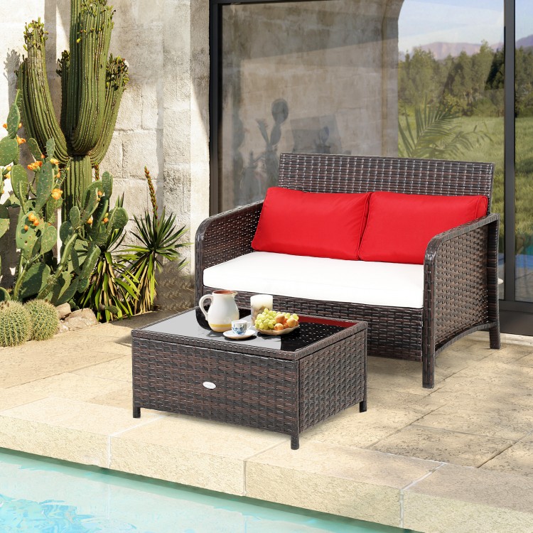 Wicker loveseat set with red cushions and coffee table, featuring hand-woven PE rattan for outdoor use by the poolside.