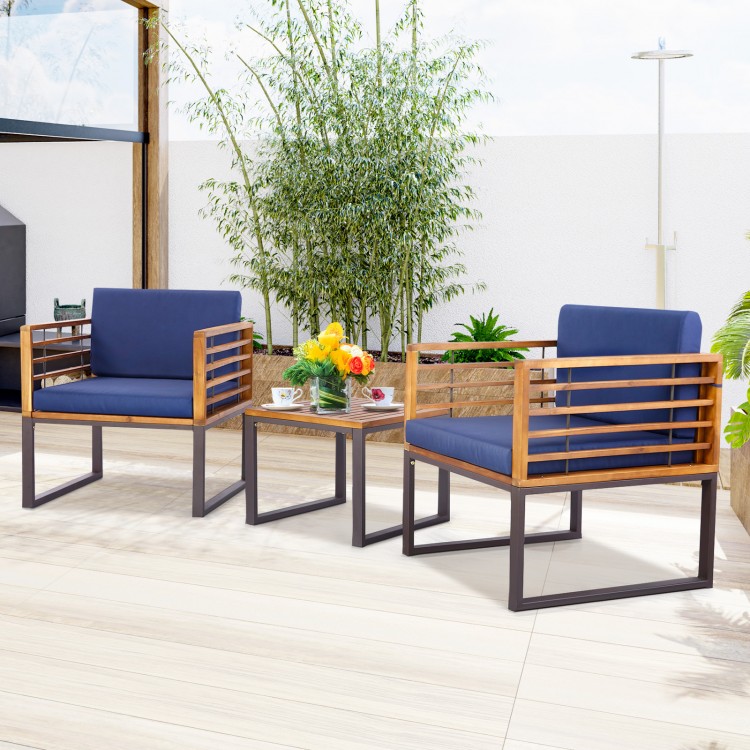 Two cushioned armchairs and a coffee table in navy, made of acacia wood, perfect for outdoor patio conversations.
