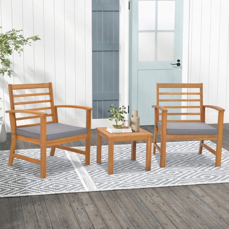 Two acacia wood chairs with gray cushions and a matching table, perfect for outdoor relaxation in any setting.