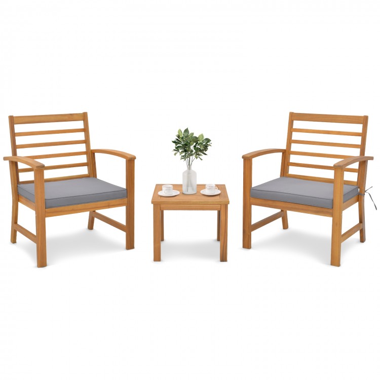 Two acacia wood chairs with gray cushions and a small table, perfect for outdoor relaxation in a backyard setting.
