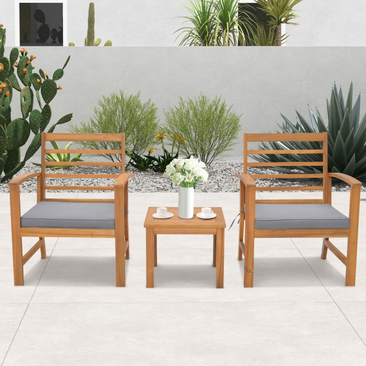 Two acacia wood chairs with gray cushions and a matching table, perfect for outdoor relaxation in a patio setting.