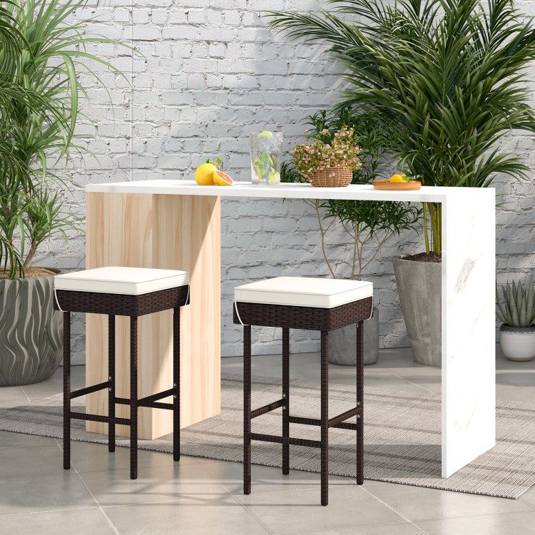 Two patio rattan barstools with soft cushions and footrests, perfect for backyard or balcony use.