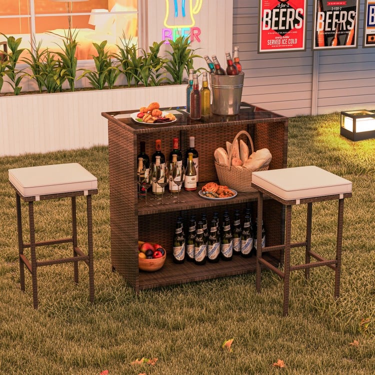 Rattan bar set with tempered glass tabletop, featuring 2-tier storage and cushioned stools for outdoor entertaining.
