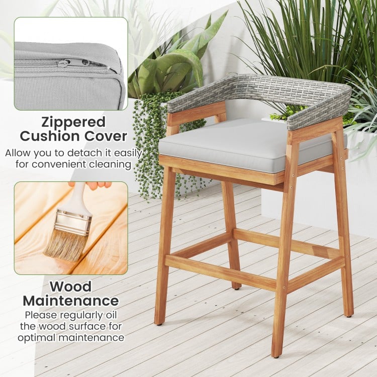 Counter height bar stool with gray cushion and PE wicker backrest, made of acacia wood for patio or garden use.