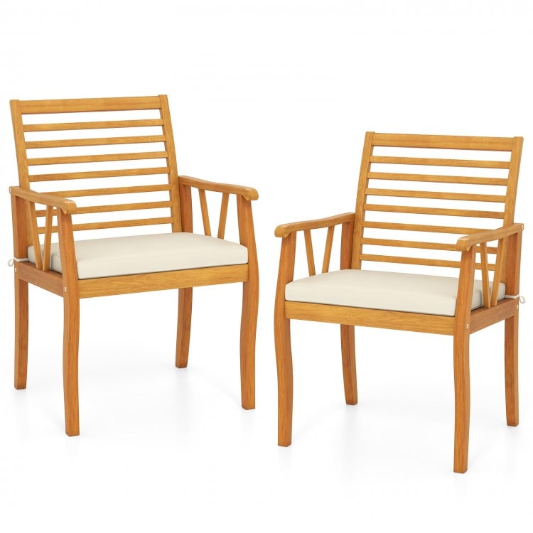 Two outdoor acacia wood armchairs with removable white cushions, perfect for patio dining and bistro conversations.