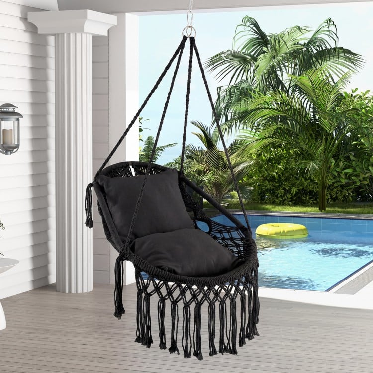 Hanging hammock chair in black with soft cushions, tassels, and sturdy rope chain, perfect for indoor or outdoor use.
