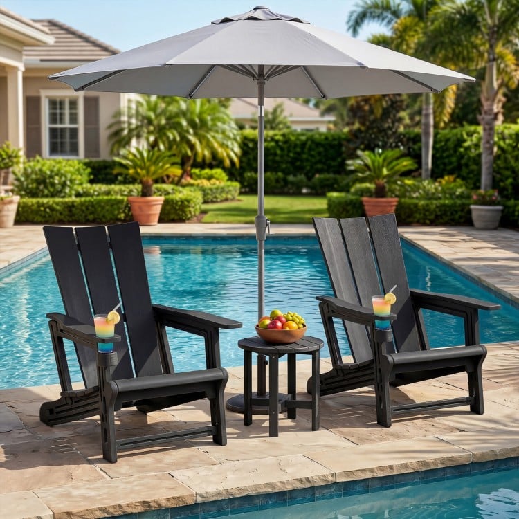Two black HDPE outdoor Adirondack chairs with cup holders beside a pool, featuring a stylish design and wide armrests.