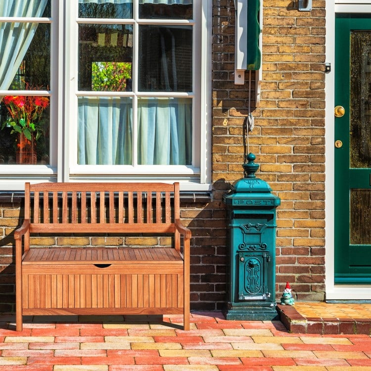 Wooden storage bench in natural teak color with a flip-top lid, perfect for patio garden seating and storage.