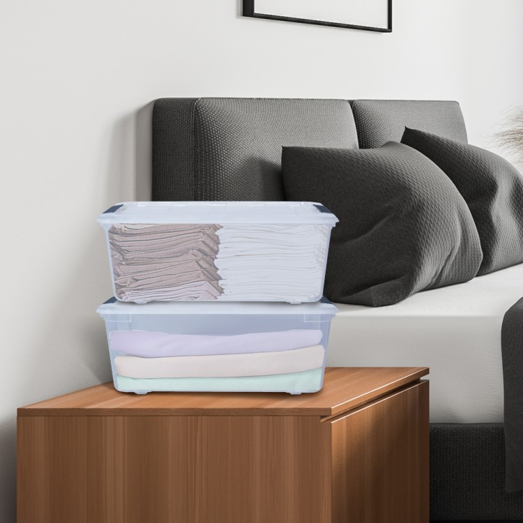 Stackable transparent storage tubs with latch closures, ideal for organizing linens on a bedside table.