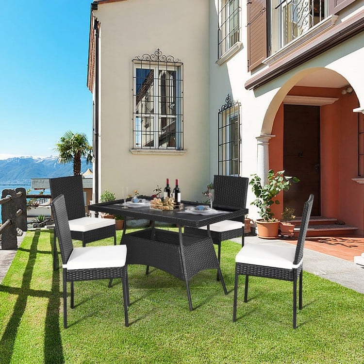 5-piece outdoor patio rattan dining set with glass top and cushions, perfect for family gatherings on the lawn.