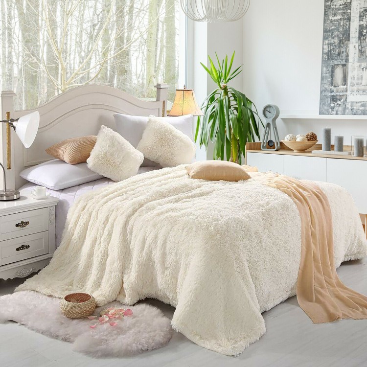 Beige double-sided throw blanket featuring shaggy fur and smooth velvet, perfect for cozying up on a bed or sofa.