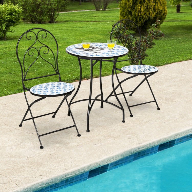 Two patio folding bistro chairs with blue floral mosaic pattern and a round table, perfect for poolside relaxation.