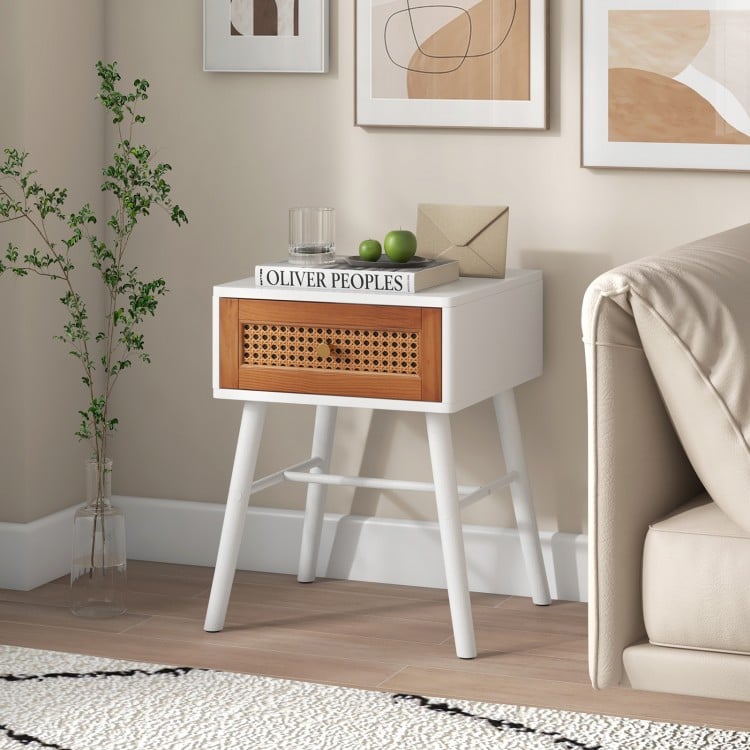 Mid-century modern rattan nightstand with a white finish, featuring a spacious tabletop and a pull-out drawer for.