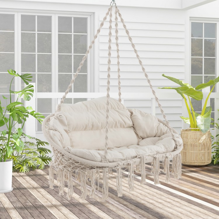 Side view of the hand-woven rope hanging chair in beige with thick cushion, highlighting the soft, durable poly-cotton.