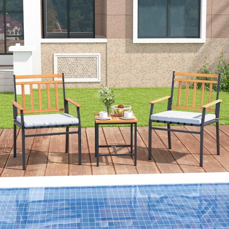 Two ergonomic outdoor chairs with white cushions and acacia wood accents, paired with a small table for patio.