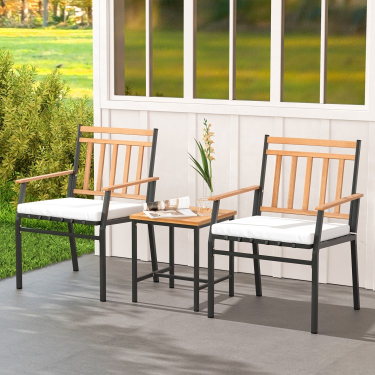 Two ergonomic chairs with acacia wood armrests and a small table, featuring white cushions for outdoor patio relaxation.