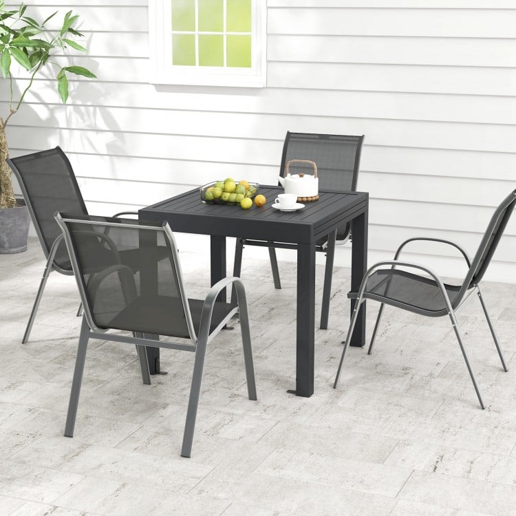 Outdoor dining table set featuring an extendable aluminum table and four stackable chairs, perfect for patios and.