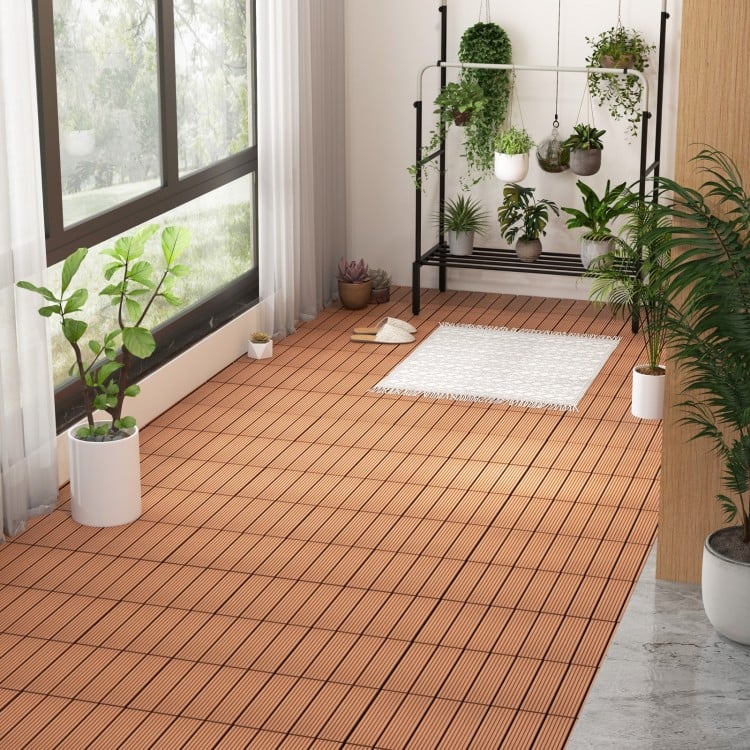 Brown 12 x 12 inch interlocking deck tiles on a floor, showcasing a slatted design for outdoor patio use.