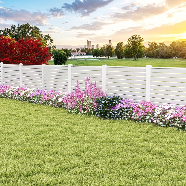 Vinyl picket fence panels in white with flowers and grass, ideal for gardens and patios, featuring durable metal stakes.