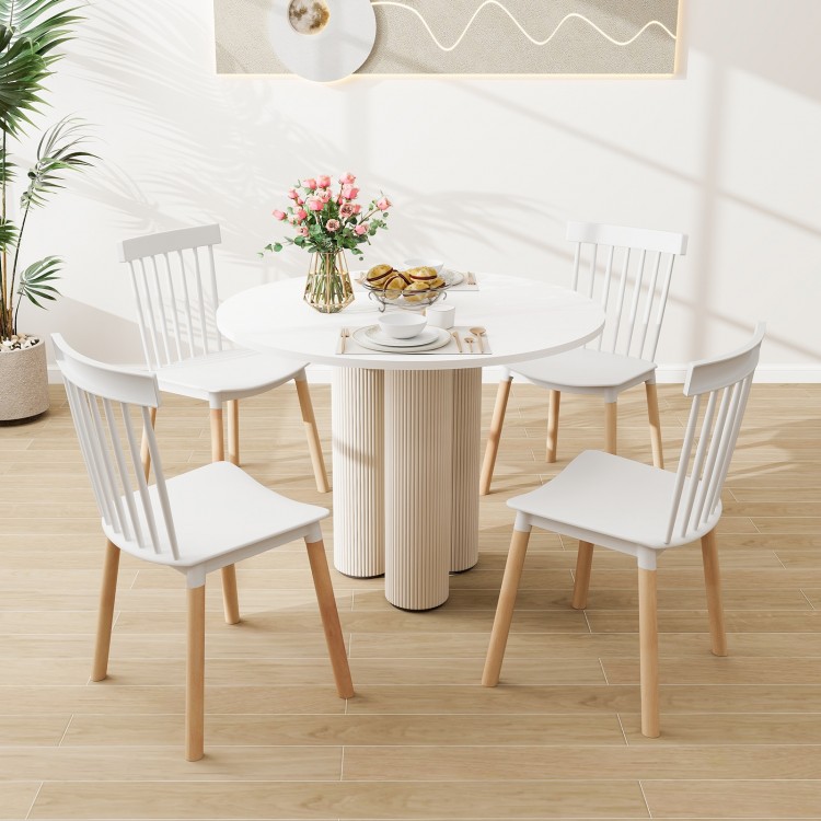 Round dining table set with four white Windsor chairs, showcasing a smooth surface and stylish spindle backs for.