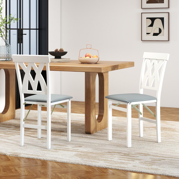 White folding wooden dining chairs with faux leather upholstery, ideal for small spaces and comfortable seating.