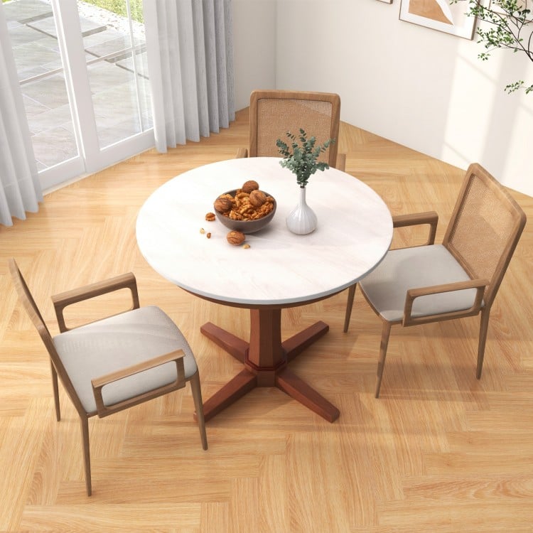 Round dining table with pedestal base in cream white finish, crafted from rubber wood, perfect for gatherings.