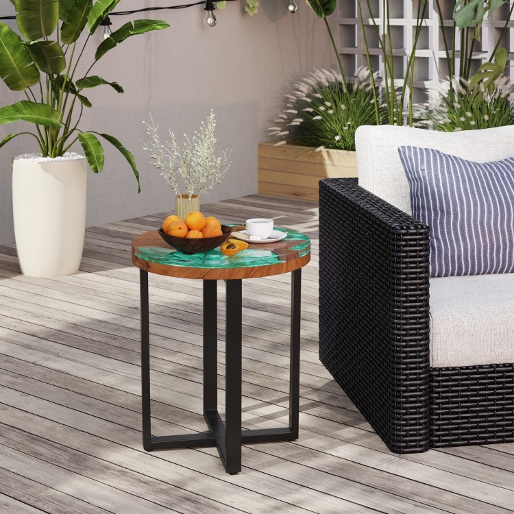 Round teak wood outdoor end table with epoxy resin top, featuring X-shaped legs, perfect for patio or balcony use.