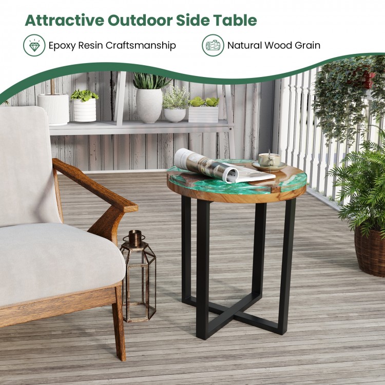 Round teak wood outdoor end table with epoxy resin top, featuring X-shaped legs, perfect for patio or poolside use.