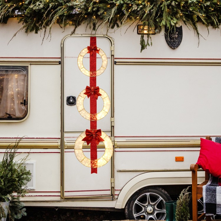 Three lighted Christmas wreaths with bows, featuring warm white LEDs, hung on a red ribbon for festive outdoor decor.