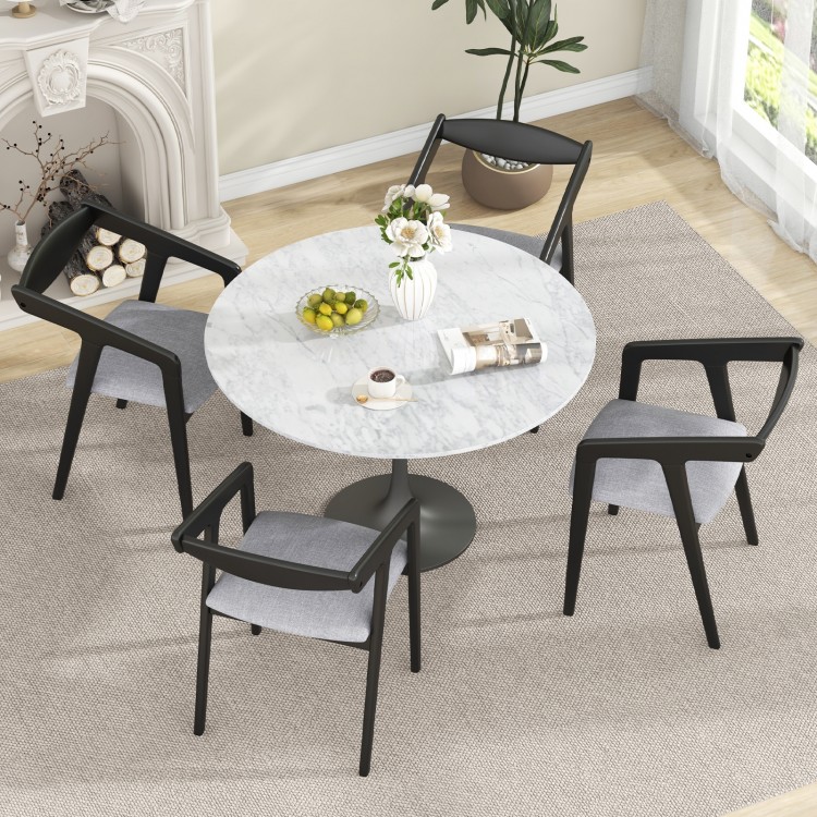 Round dining table with four black wooden chairs featuring padded cushions and ergonomic armrests for comfortable.
