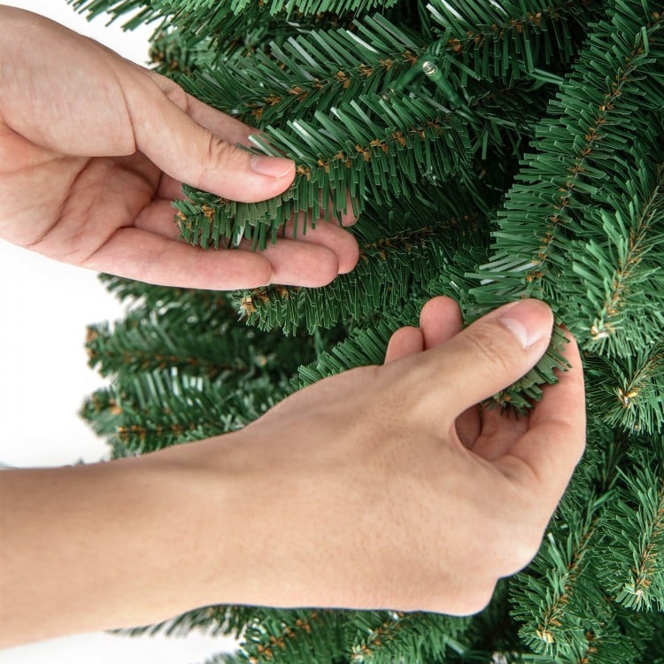 Hands adjusting the branch tips of a 5FT Pencil Christmas Tree with memory wire and warm LED lights for festive.