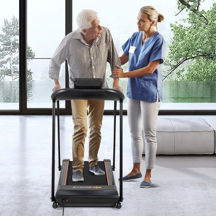 Senior using a 2.5 HP walking treadmill with long handrails, featuring an LED display and safety key for enhanced.