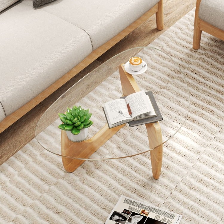 Triangle coffee table with a natural rubber wood base, featuring a clear glass top and ample space for magazines and.