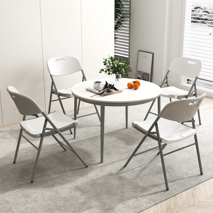 Round table set with four white folding chairs, featuring a metal frame and ergonomic design, ideal for versatile.