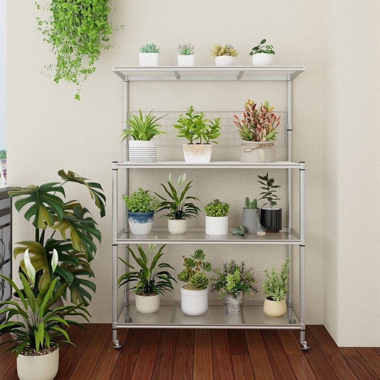 4-tier silver bakers rack on wheels with adjustable shelves and plants, ideal for kitchen organization and storage.