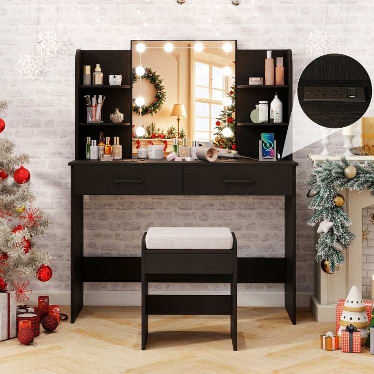 Black vanity set featuring a lighted mirror, cushioned stool, and storage drawers, perfect for makeup application.