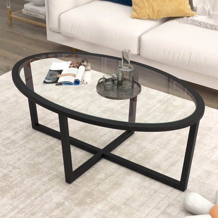 Oval glass coffee table with black acacia wood legs and cross base, perfect for living room decor and stability.